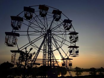 Low angle view of ferris wheel against sky at sunset