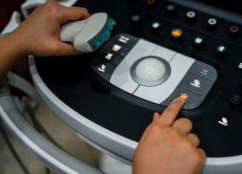 Close-up of hand holding ultrasound machine button with gel