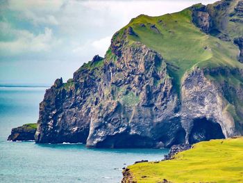 Scenic view of cliff by sea against sky