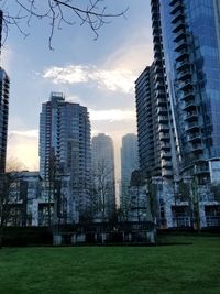 Skyscrapers in city against sky at sunset