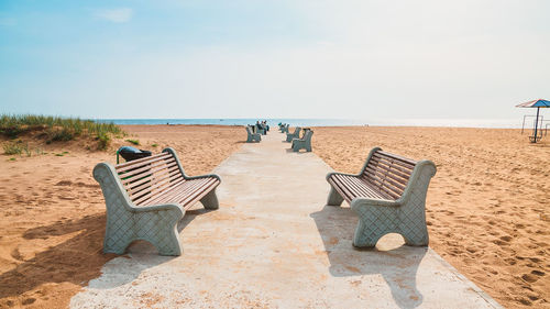 Deck chairs on beach against sky