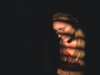 Close-up of woman standing against black background