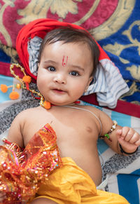 Cute indian boy dresses as lord rama with bow and flowers from top angle