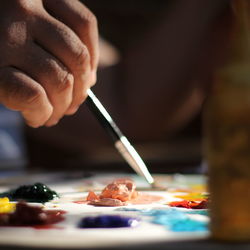 Close-up of hand holding paint brush to palette