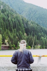 Rear view of woman standing on road against trees