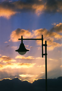 Low angle view of silhouette street light against orange sky