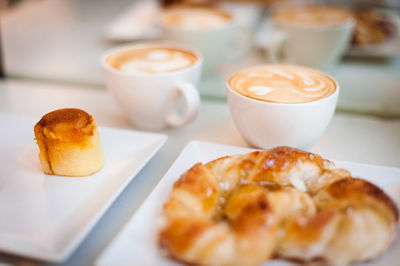 High angle view of dessert with cappuccinos and croissant served on table