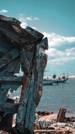 Close-up of driftwood on wooden post by sea against sky