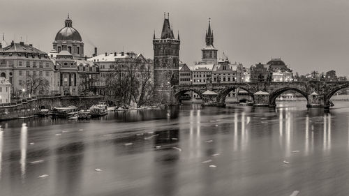 Bridge over river by buildings in city