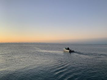 Scenic view of sea against clear sky and a boat during sunset