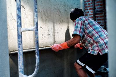 Worker plastering the cement texture on the brickwork wall with the shadow at construction site