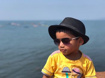 Boy wearing sunglasses and hat against sea
