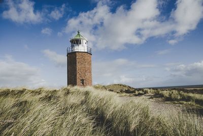 Lighthouse on field against sky