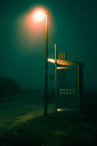 Illuminated street light against sky at night