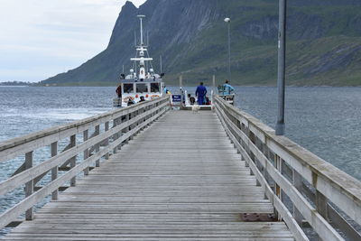 People on pier over sea against sky