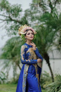 Portrait of beautiful young woman standing against plants