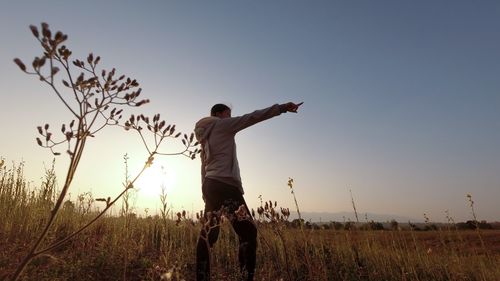 Low angle view of woman gesturing while standing in field against sky