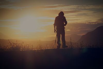 Silhouette man standing on shore against sky during sunset