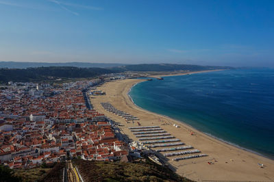 High angle view of buildings by sea against blue sky