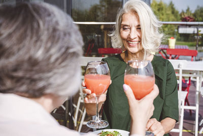 Smiling woman having juice with female friend at restaurant
