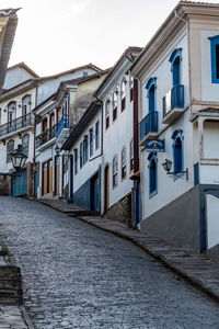 Houses by street in city against sky