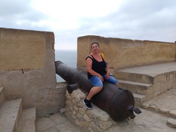 Full length of woman sitting against sky