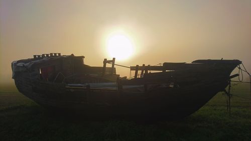 Boat moored on beach against clear sky during sunset