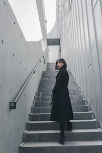 Full length of woman standing on staircase