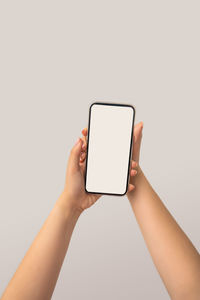 Low section of person holding smart phone against white background