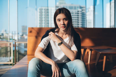 Portrait of beautiful young woman sitting on chair in restaurant