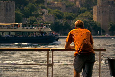 Rear view of man standing on ferry at lake