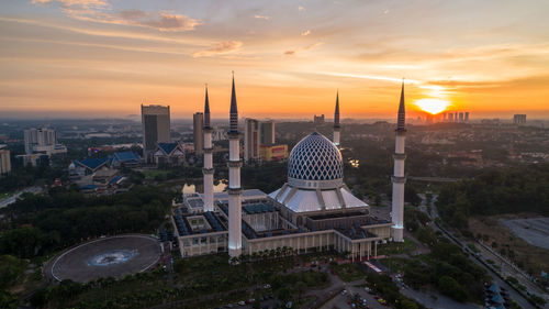 Modern buildings in city against sky during sunset