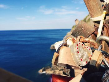 Close-up of love locks on railing by sea