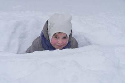 Portrait of girl lying on snow covered landscape