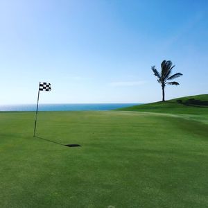 Flag on golf course against clear sky