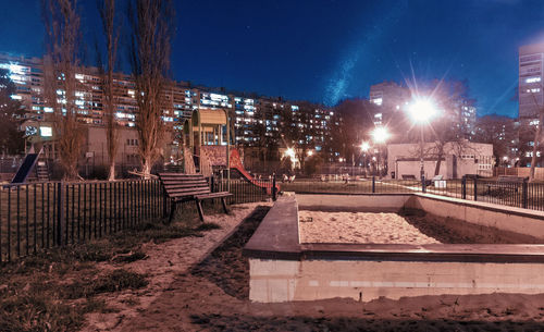 Illuminated street amidst buildings in city at night