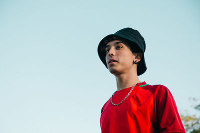 Portrait of young man looking away against clear sky