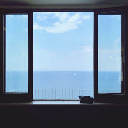 Open window view of the blue sea with silhouetted typewriter 