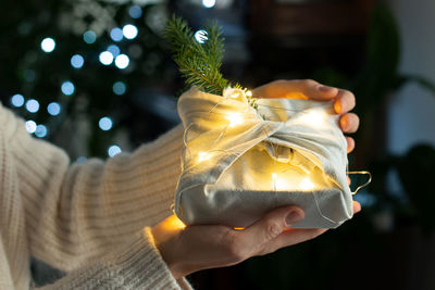 Cropped hands of woman holding illuminated christmas decoration