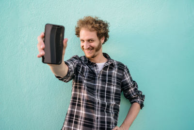 Portrait of smiling young woman standing against wall