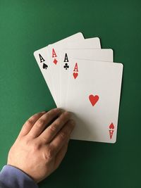 High angle view of man with aces cards on green table