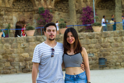 Portrait of happy friends standing against brick wall