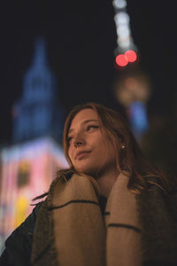 Fashionable young woman in city at night