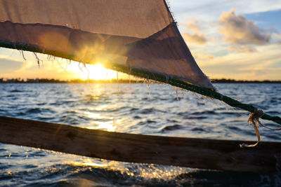 Close-up of sailboat in sea against sky during sunset