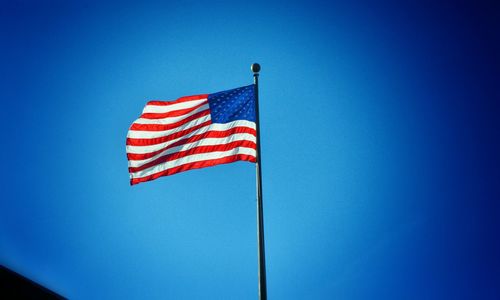 Low angle view of american flag against clear blue sky