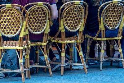 Low section of people sitting on wicker chairs