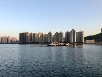 Sea and modern buildings in city against clear sky