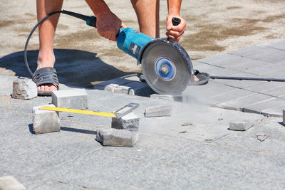 A worker cuts paving slabs with a grinder with a diamond blade. selective focus, copy space.