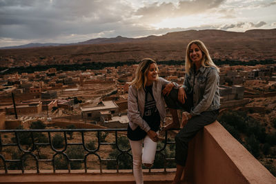 Woman standing by people on mountain against sky