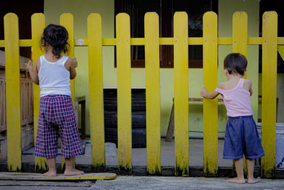 Full length of a girl standing against yellow building